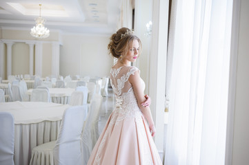 A beautiful woman in a pink wedding dress in a big festive hall