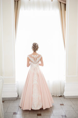 A beautiful woman in a pink wedding dress in a big festive hall