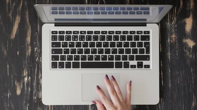 Female user hand clicking on the touchpad of the silver laptop