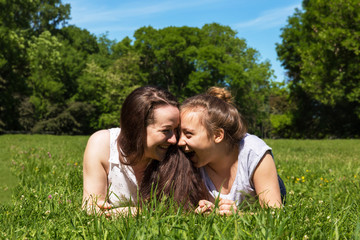 Two girls look to each other and laugh. City park.