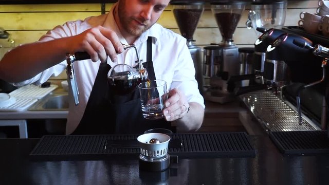 Barista in coffee shop pouring Syphon coffee into glass