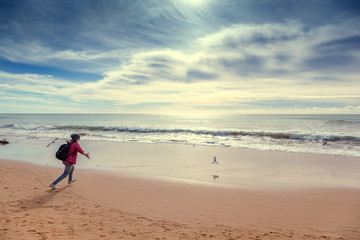A girl traveler runs after seagulls on the ocean, a beautiful seascape. Portugal, Algarve