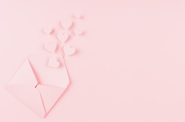Opened paper envelope with fly out hearts on soft pink color background. Copy space. Valentine day concept for design.