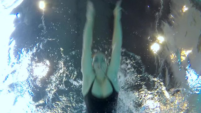 Young Woman Swimming Breaststroke in the Pool Underwater/Young woman swims breaststroke in the pool. The camera is underwater. She's very pretty and slim. Swiiming is the way to stay fit