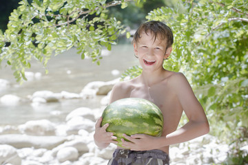 Fototapeta premium Teenager boy holding fresh green watermelon in his hands