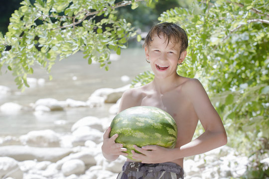 Teenager boy holding fresh green watermelon in his hands