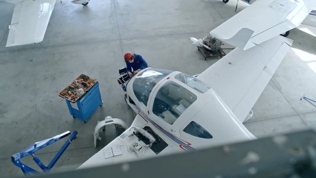 High angle view of female aircraft mechanic repairing airplane engine with instruments in hangar