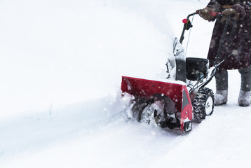Man clears snow with snowblower after winter snowfall
