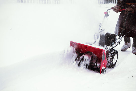 Man clears snow with snow blower after winter snowfall