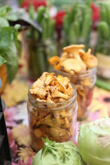 Local Farmers Market. Fresh produce: vegetables, berries, wild flowers. Chanterelle / girolle (Cantharellus cibarius) edible mushrooms in the glass mason jars. Lithuania.