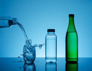 Creative splashing water in the glass on blue background.