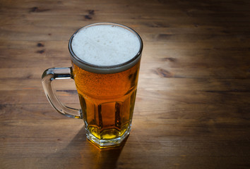 Glass of golden beer on wood background