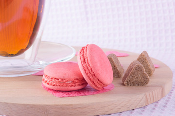 a mug of tea with two cookies macaron, on a wooden board and sugar like a heart