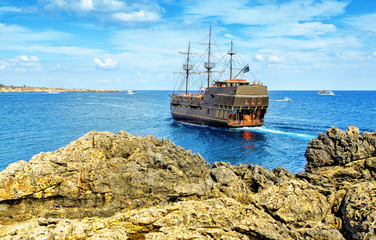 The bridge of love or love bridge. Pirate ship sailing near famous Bridge of Love near Ayia Napa, Cyprus.