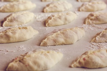 Raw homemade pies lie on the table with flour