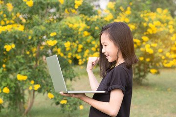 Asian girl is using a laptop in the garden