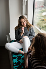 Mother and daughter biting off chocolate at home