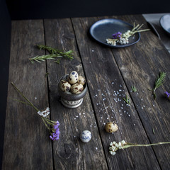 Quail eggs in metal rustic bowl on wooden country table in interior