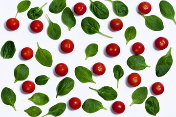 Tomatoes and spinach leaves on a white background.
