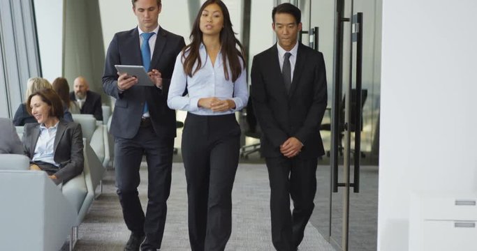 4K Demanding lady boss giving orders to assistants as they walk through city office. Slow motion.