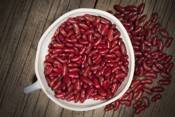 Red beans in a ceramic cookware on old wood