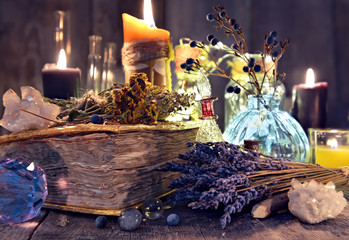 Old witch book with lavender flowers, crystal and evil candles. Occult, esoteric, divination and wicca concept. Halloween background with vintage objects 