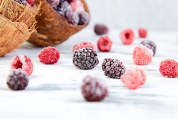 Frozen black and red raspberries in coconut bowl.