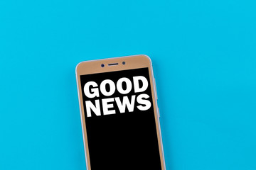 Good news inscription on phone screen. Golden phone on a blue background