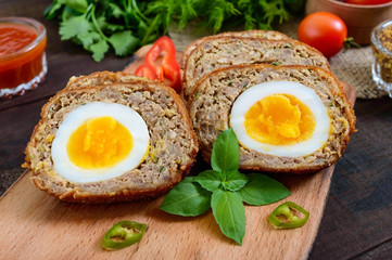 Meat cutlet with boiled egg, pieces on a dark wooden background. Mini meat rolls. Scottish cutlet.