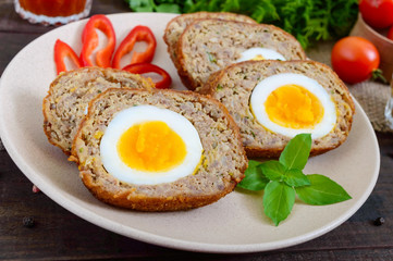 Meat cutlet with boiled egg, pieces on a dark wooden background. Mini meat rolls. Scottish cutlet.