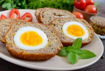 Meat cutlet with boiled egg, pieces on a ceramic plate on a dark wooden background. Mini meat rolls. Scottish cutlet.