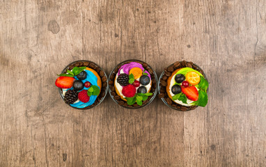 Cakes with berries and mint on a wooden background