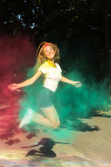 Fototapeta na wymiar Cheerful young woman jumping with vibrant colors exploding around her
