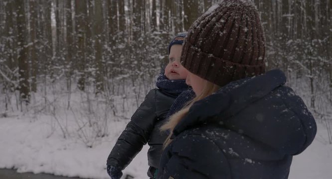 Mother and child are walking through the forest, in winter, all in white snow and trees.