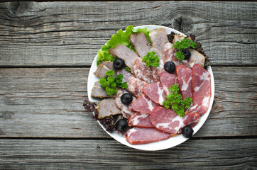nicely sliced meat on plate, on wooden background in rustic style