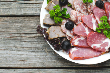 nicely sliced meat on plate, on wooden background in rustic style