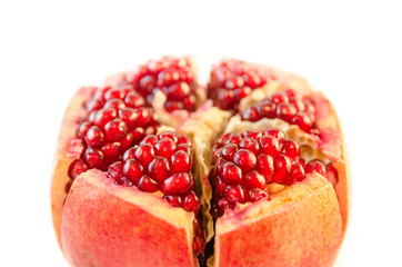 Ripe red pomegranate and seeds close-up in foreground isolated on white background out-of-focus blurred macro
