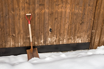 Old rusted shovel in the snow outside a garage port