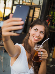 smiling woman making selfie with a drink on a party