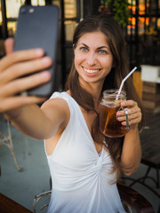 smiling woman making selfie with a drink on a party