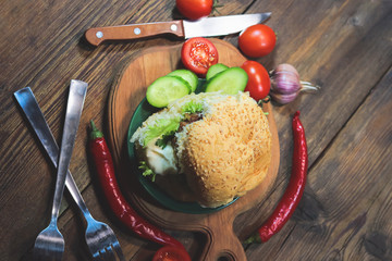 loaf with cutlet and vegetables on wooden table. hamburger