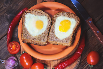 fried bread. fried eggs in a heart-shaped symbol. vegetables. on a wooden board