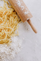 Tasty fresh appetizing raw pasta with flour and eggs on bright table. Top View.