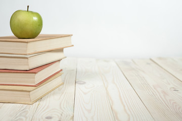 Stack of books and apple on the table