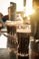 Close up of a glass of stout beer in a bar - obrazy, fototapety, plakaty