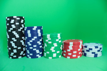 Poker concept. Bright different chips in a row, rating. Green background