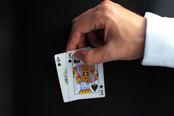 Man's hand holds a poker cards. Poker concept on black background. Close up. 