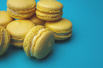 Stack of yellow macaroons on blue background. Colorful almond cookies. Pastel cake macarons background. Place for text.