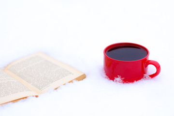 Red cup of coffee or tea with a red book or notebook or photo albums with heart. Snow is coming. Winter concept of Valentine's Day