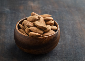 Group of Peeled almonds in wooden bowl on rustic wooden table. Almonds background. Horizontal. Copy space.
